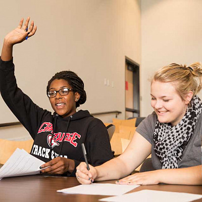 Student raising their hand in a classroom.