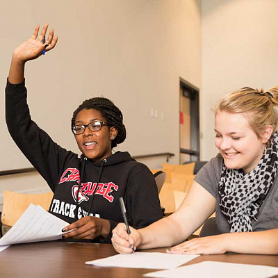 Student raising their hand in a classroom.