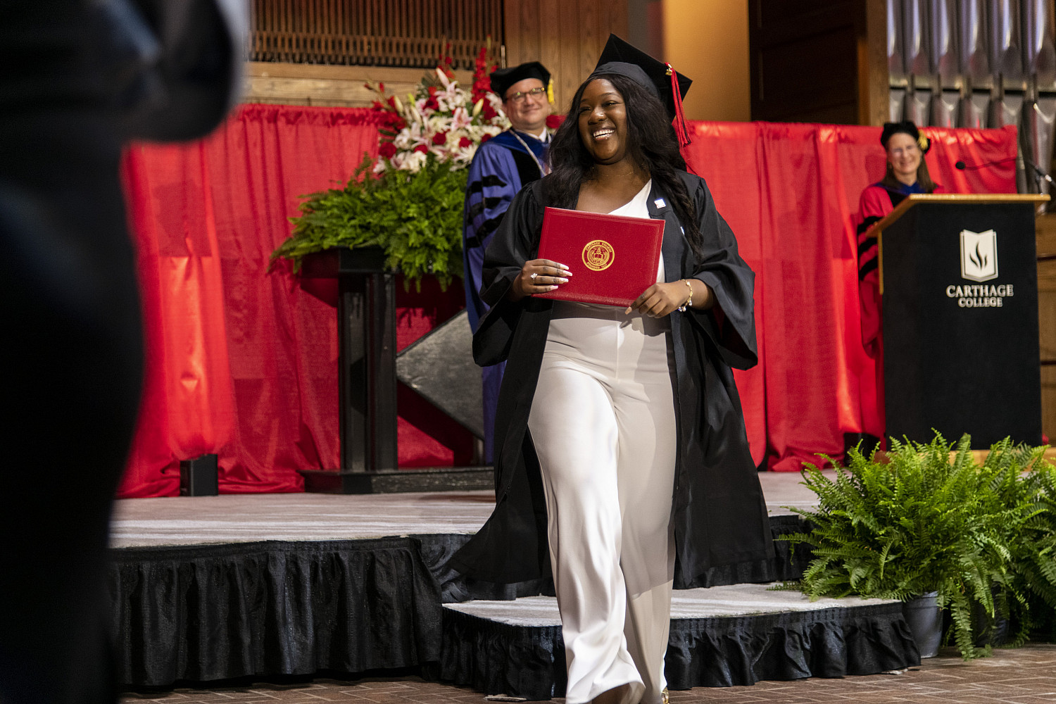 A 2023 Carthage College graduate beams as she leaves the Commencement stage after receiving her diploma from Carthage President John Swallow.