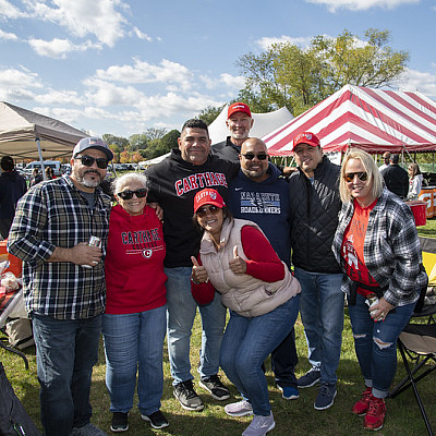 A small group of people in Carthage clothing in front of outdoor tents.
