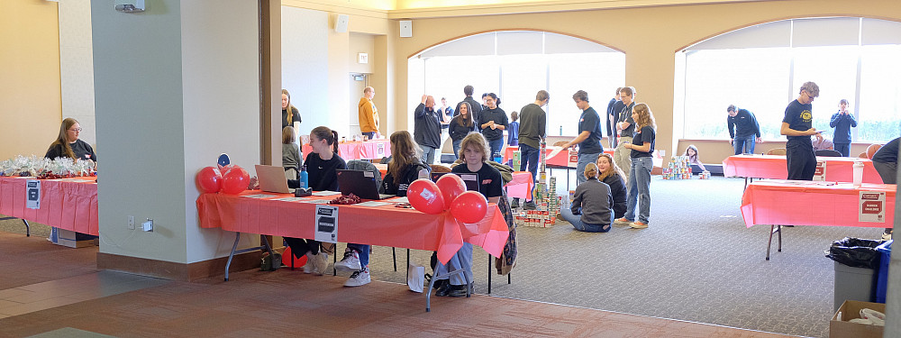 Engineering students sitting at various tables as they prepare for an event.