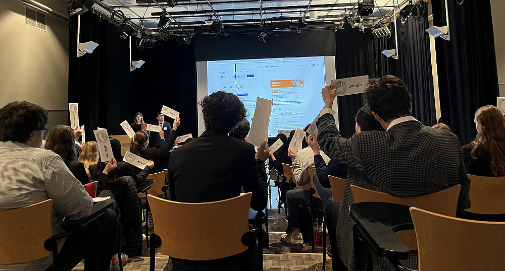 High school students hold up papers with the country they are representing for Model UN.