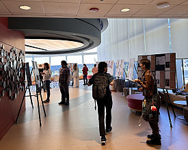 Students walk through a gallery with information on Women in Stem