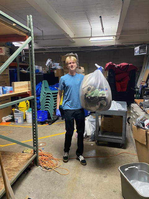 A student holding a garbage bag of winter clothes.