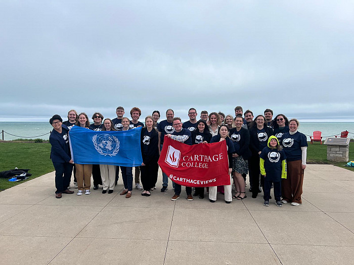 Current and past members of the Carthage Model United nations gathering for a group photo by the lake.