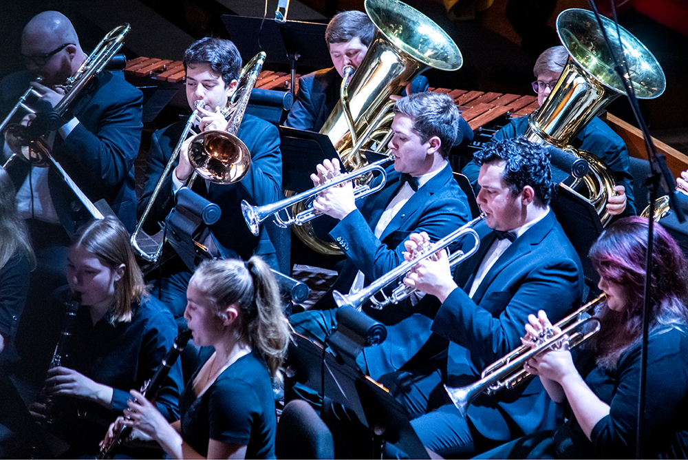 A photo of students performing their instruments at a music concert.
