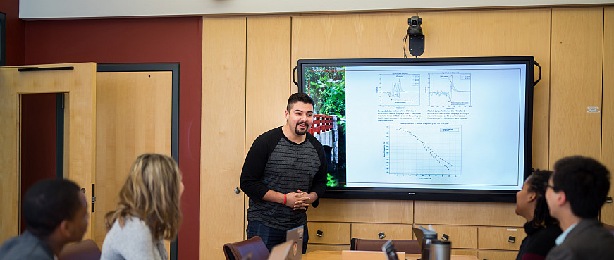 A student gives a presentation on a screen in a classroom.