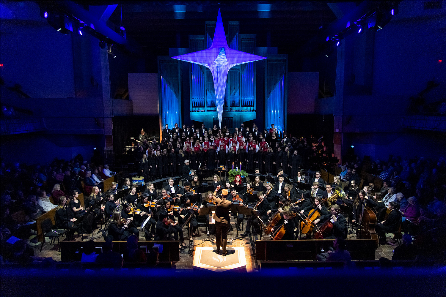 Carthage musicians and singers performing in the chapel, which is decorated with blue lights and a large star on the ceiling.