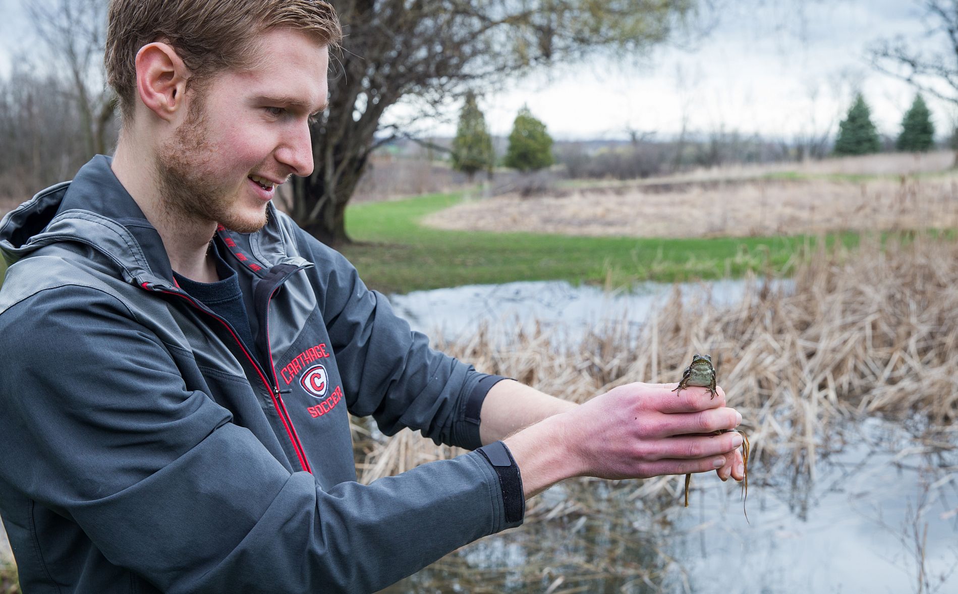 An environmental science major holding a toad while doing research.