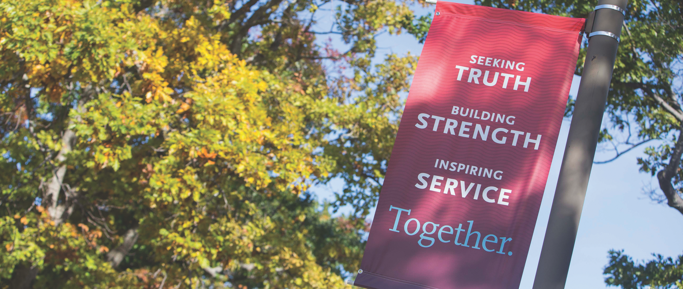 A banner on Campus Drive displays the Carthage College mission statement: Seeking Truth, Building Strength, Inspiring Service: Together.