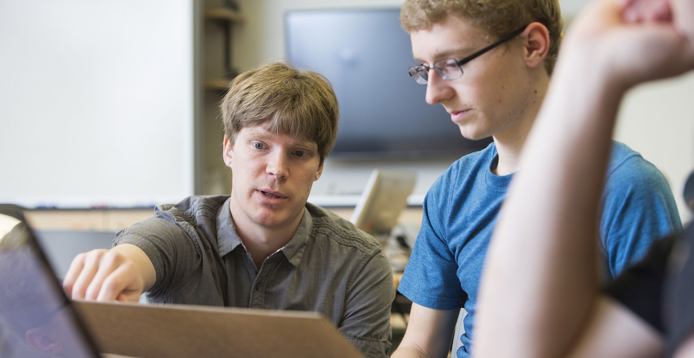 Prof. Brant Carlson assists a physics major student during a physics class.