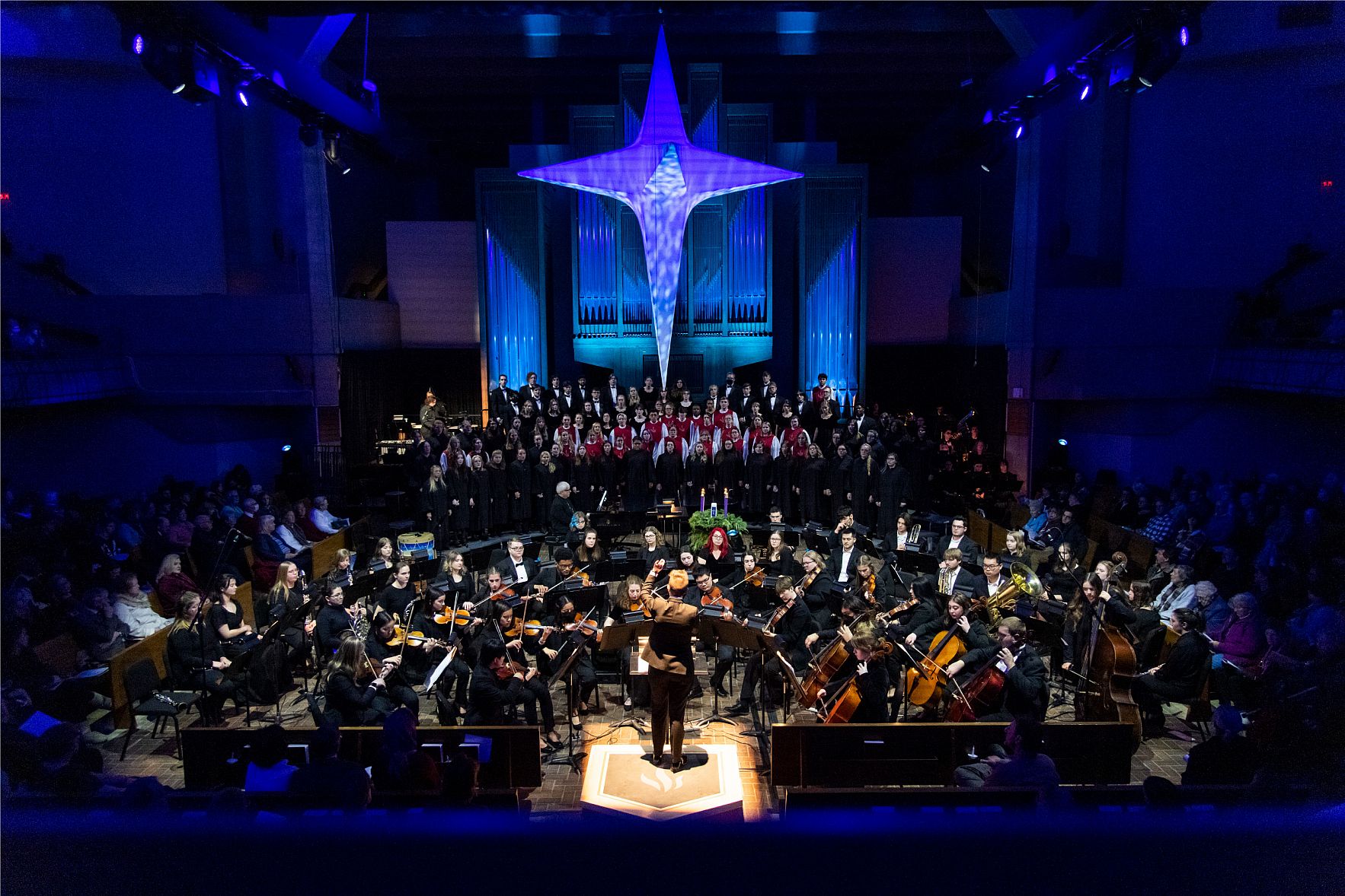 Carthage musicians and singers performing in the chapel, which is decorated with blue lights and a large star on the ceiling.