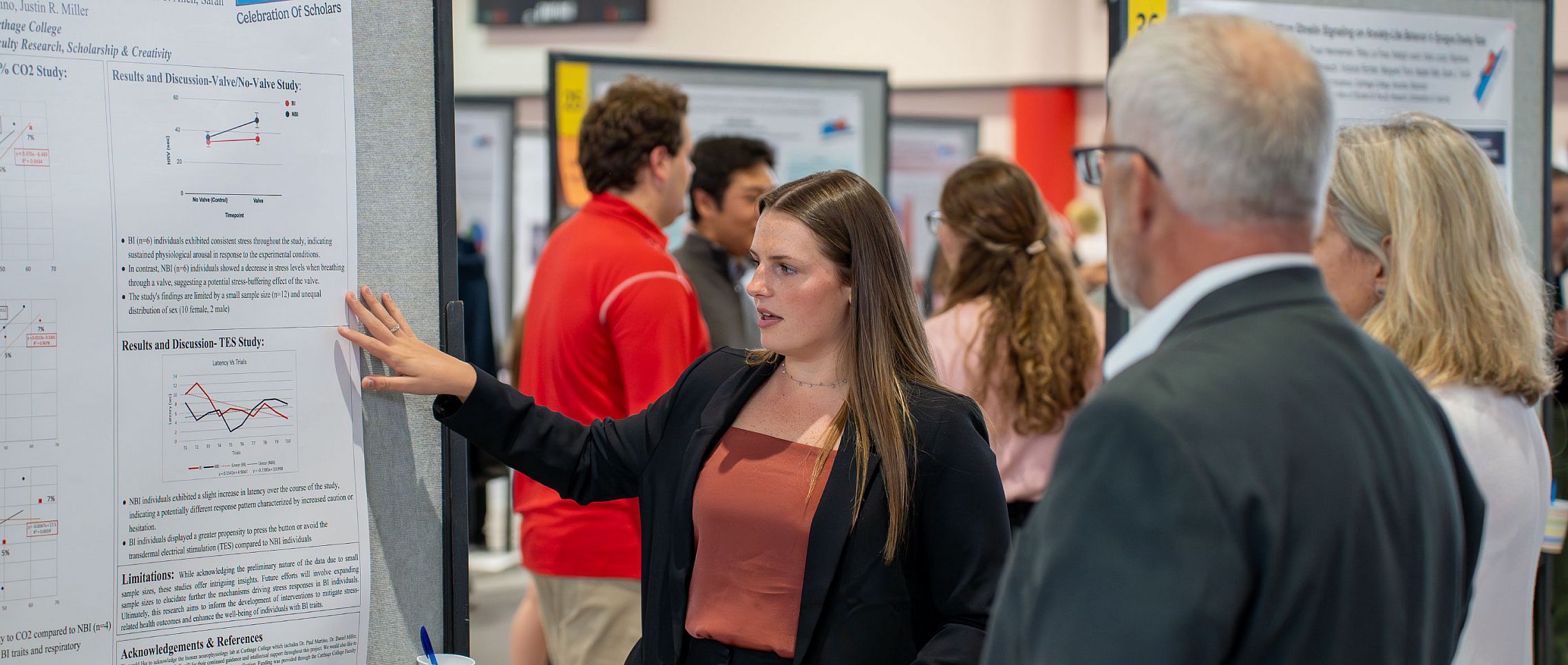 A student presenting a poster to a group of individuals.