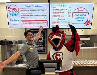 Carthage College mascot Ember and a dining staff member show off the diner's menu.