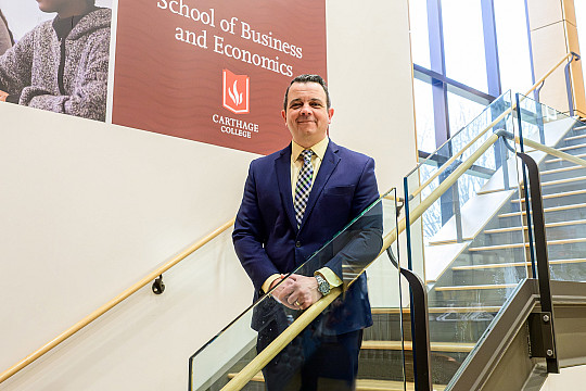 Joseph Tenuta stands in front of School of Business and Economic banner